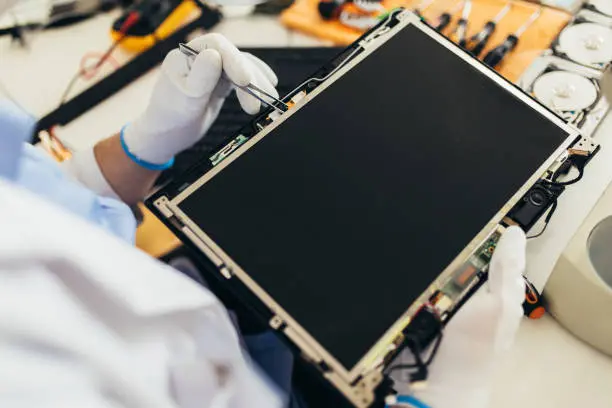 إيدين فني بجوانتي بتمسك بانل شاشة LCD أثناء الفك